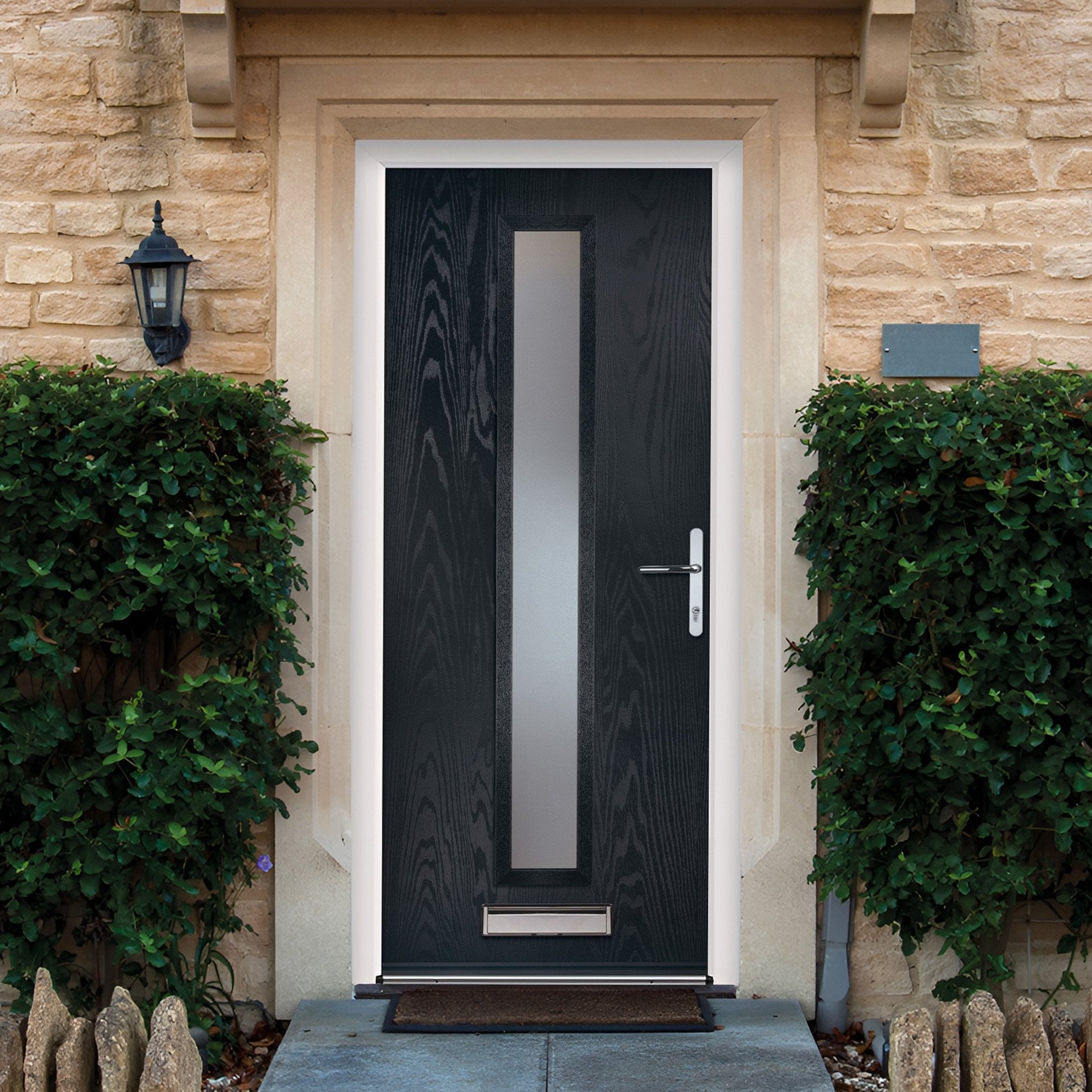 Black composite door with decorative glass panel on a stone building facade.